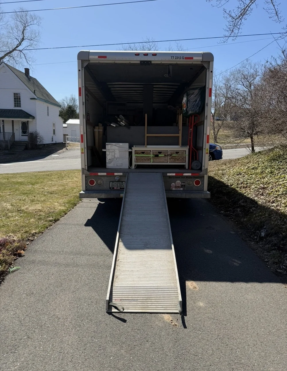 Middle Man Movers box truck backed into a Nova Scotia driveway with its loading ramp down and furniture stacked inside.