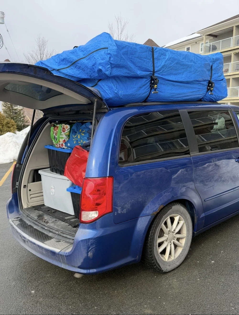 Storage totes and a tarp-wrapped mattress loaded into a van for a small Halifax move.